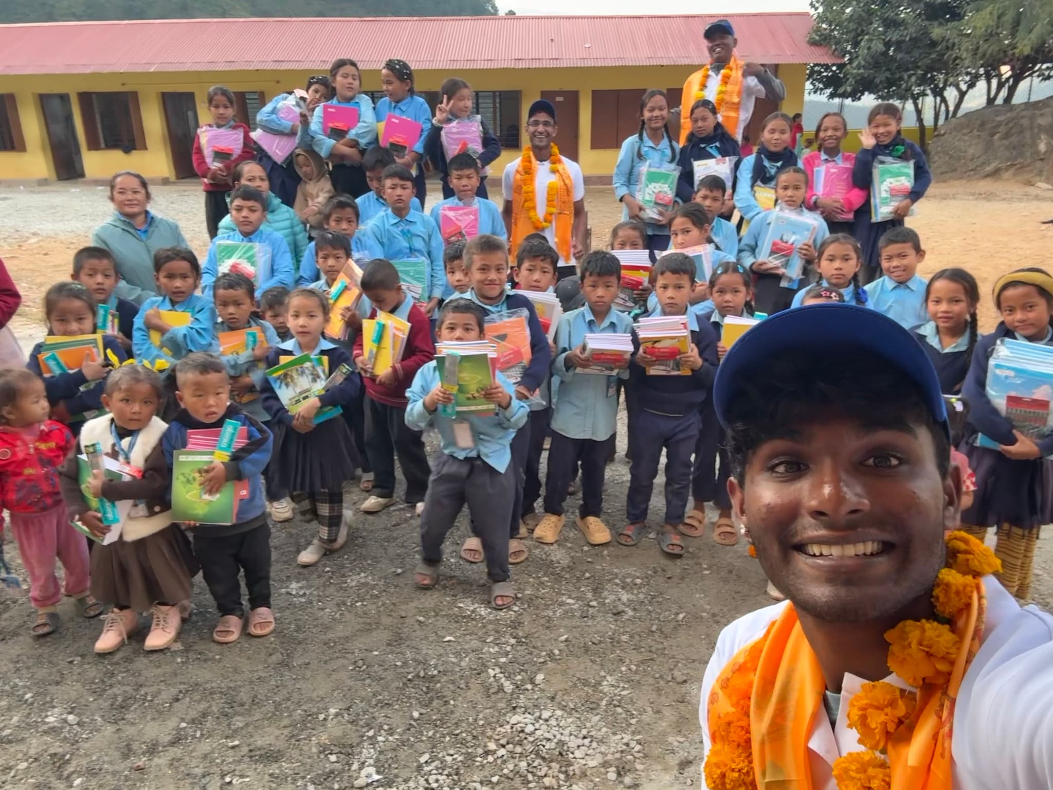 Dr Devang Krishna with schoolchildren in the mountains of Nepal, each holding the textbooks and resources Milestone sponsored.