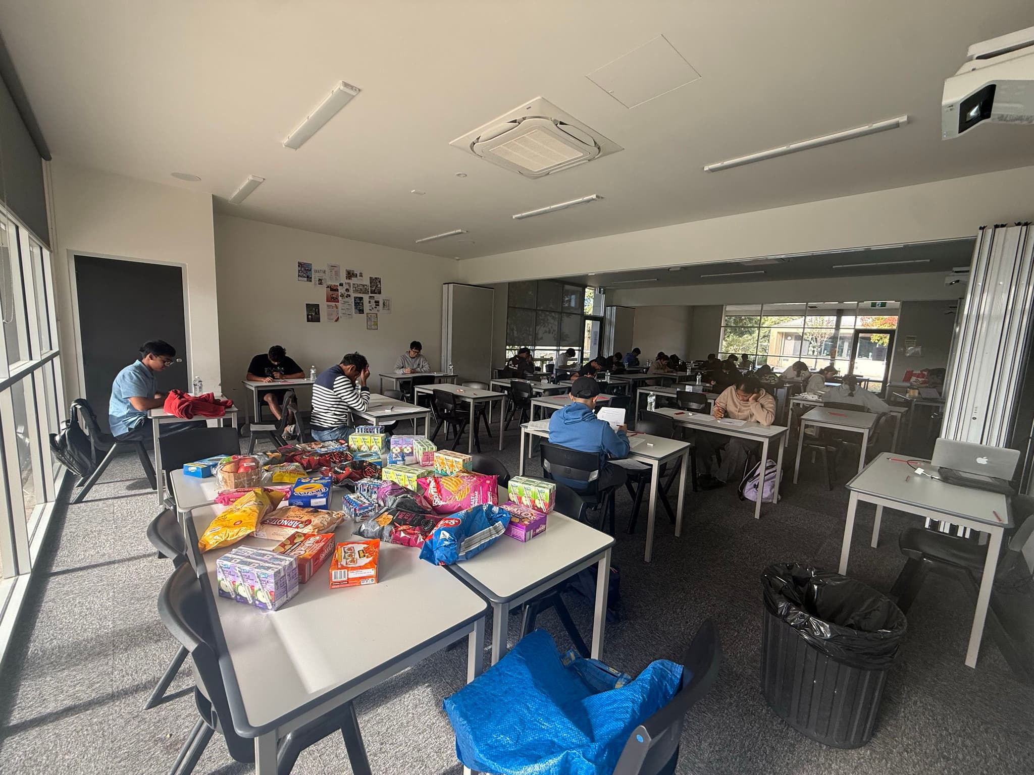 A weekend class in session, students working at desks with snacks laid out on a shared table.